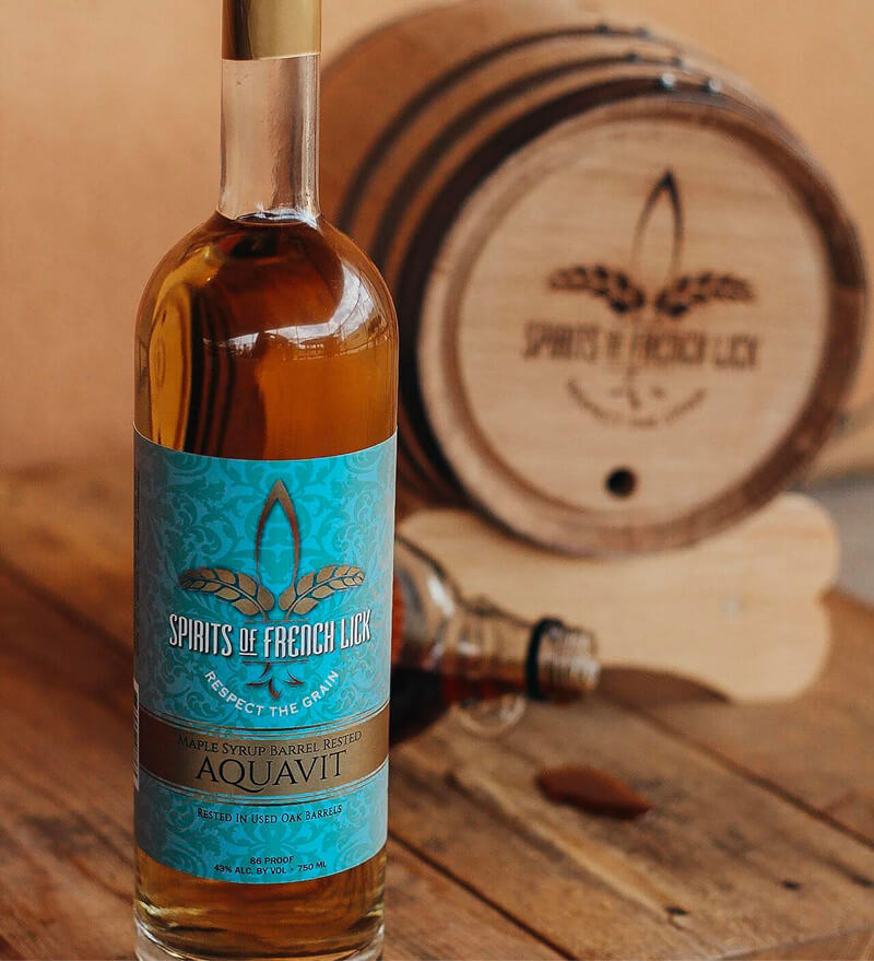 A bottle of wine next to a small cask.